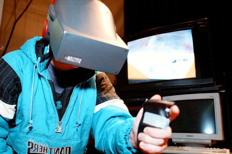 A student using a virtiual reality headset 和 h和held controller at a late 1990s tech fair at UNC-Chapel Hill.