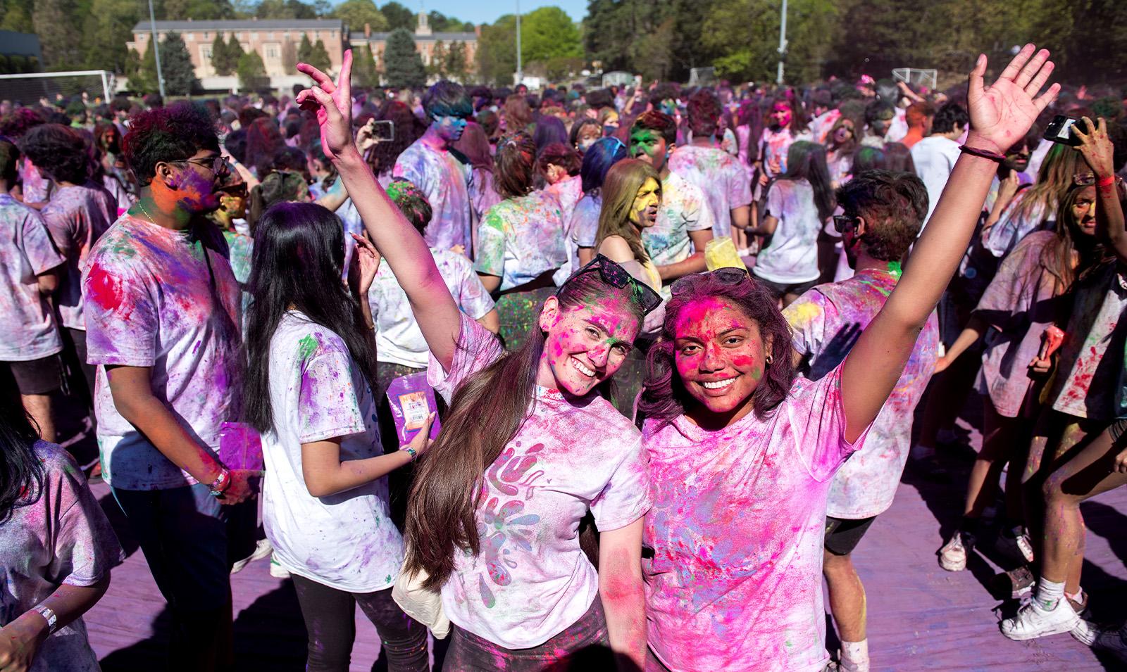 Two students covered in paint celebrating Holi.