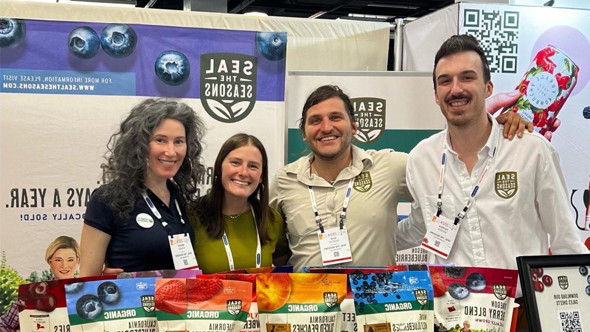 Two men and two women posing next to products wearing 