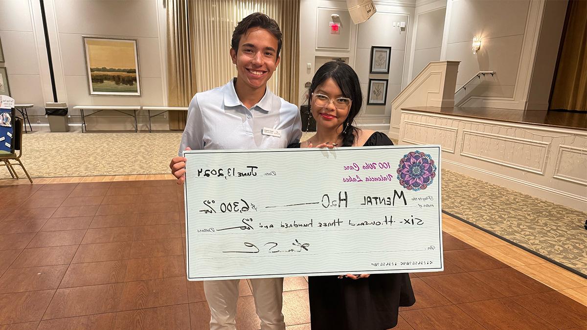 Carolina students Idania Rodriguez (left) and Garrett Livingston holding an oversized check for their nonprofit - Mental H20.