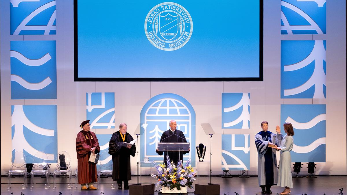 Wide-angle shot of the stage in Memorial Hall on the campus of UNC-Chapel Hill during the inauguration of Chancellor Lee H. Roberts on University Day. Roberts is seen taking his oath of office with his hand on the Bible.